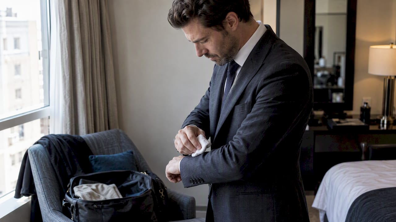 Man blotting a mark on his suit sleeve